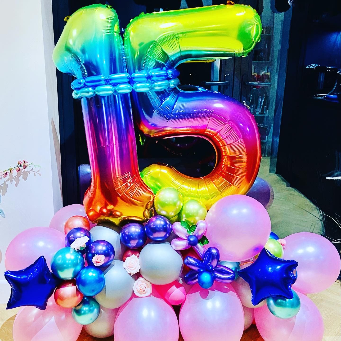 Rainbow number 15 balloon stack with pink base and flowers