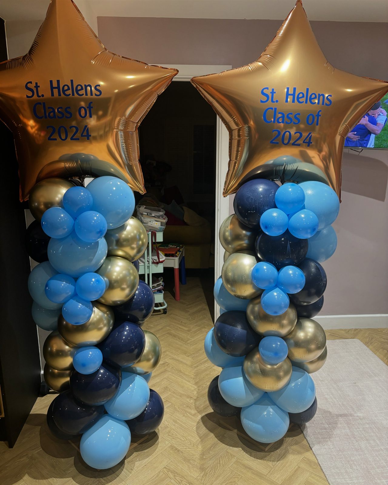 Twin blue and gold balloon columns with personalised star toppers