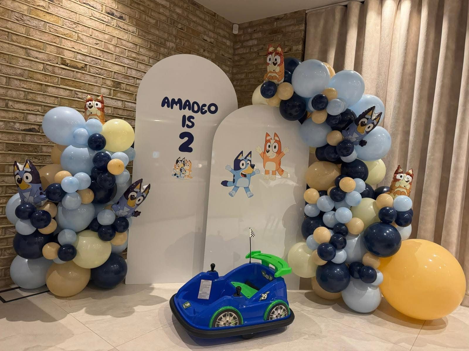 Cartoon dog themed arched backdrop boards with balloon garlands for a second birthday